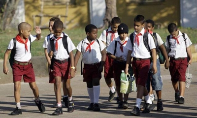 Niños cubanos vestidos de uniforme de primaria caminan por las calles
