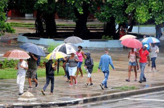 Personas protegiéndose de la lluvia al transitar por el Vedado, en La Habana. Foto: Omara García Mederos/ ACN.