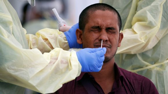 Médicos extraen muestras nasales a un trabajador en Singapur, 15 de mayo de 2020. Foto: Reuters.